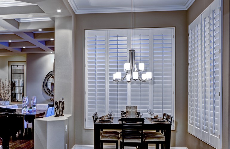 White plantation shutters on two walls of modern dining room